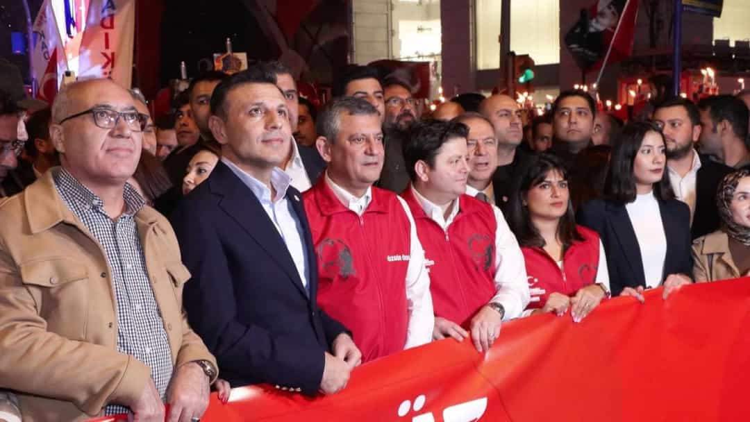 Özgür Özel, kalabalıkla birlikte kırmızı bir pankartın arkasında yürürken