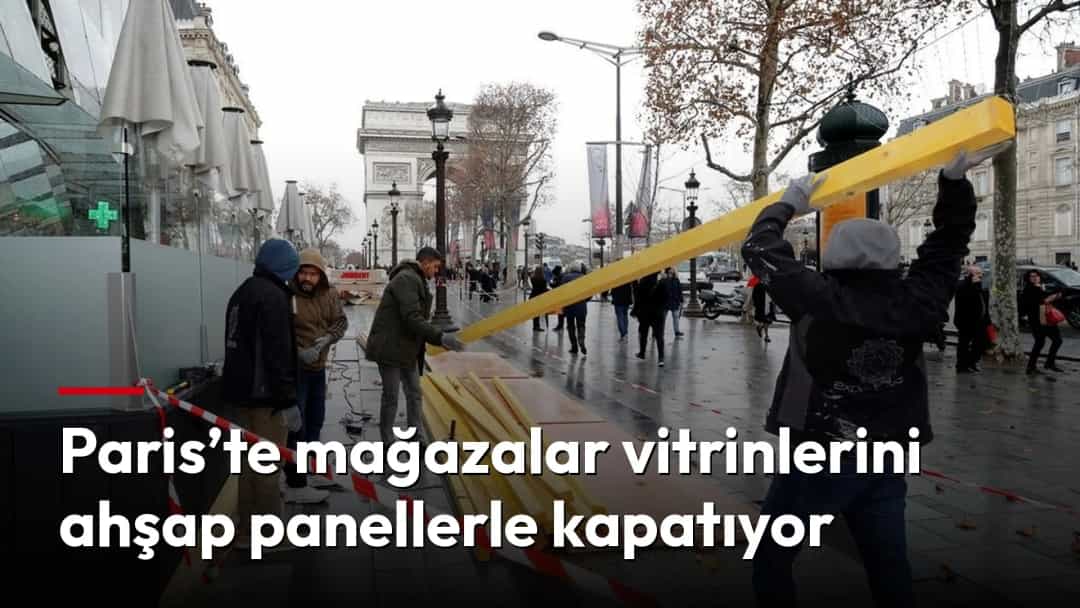 Paris’te bir mağazanın önünde işçiler vitrinleri korumak için ahşap paneller taşıyor.