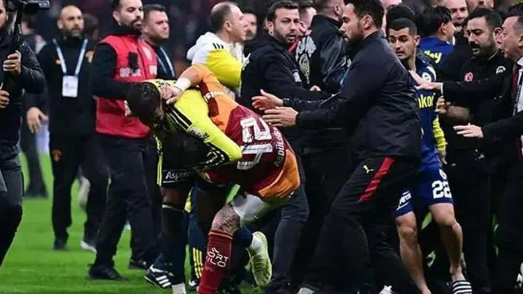 Derbi sırasında sahada yaşanan gerginlikte Galatasaraylı Abdülkerim Bardakcı yere doğru eğilirken çevresindeki futbolcular ve görevliler araya giriyor.