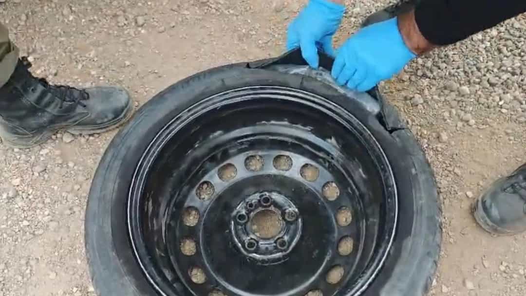 Görevliler, inceleme için otomobilin yedek lastiğini kontrol ediyor.