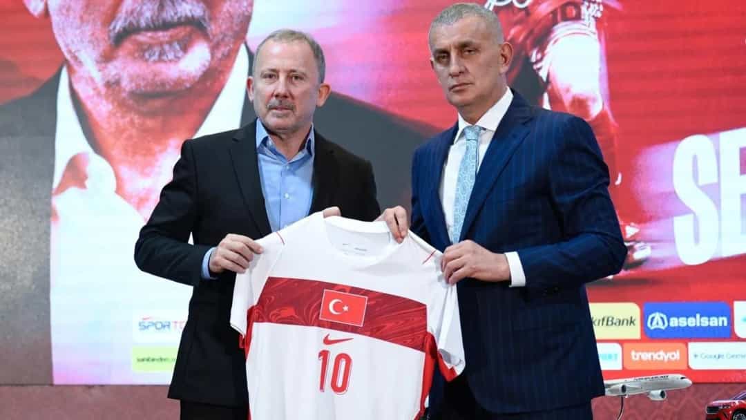 Sergen Yalçın, milli takım forması tutan iki kişiden soldaki olarak bir forma tanıtım etkinliğinde.