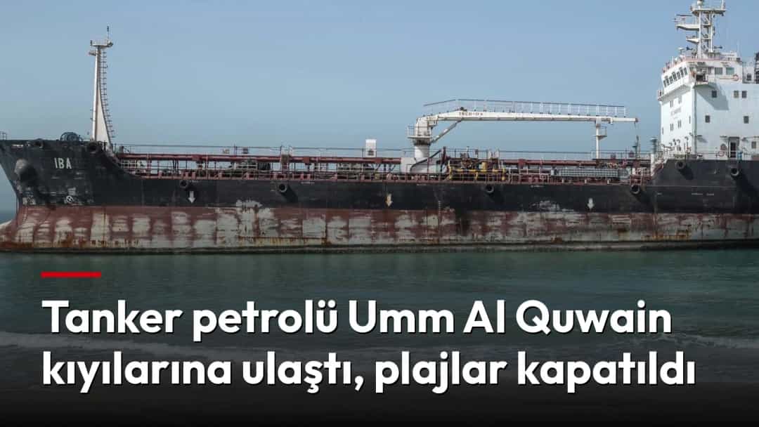 Kıyıya yakın denizde büyük bir tanker duruyor; ön planda sahilde yürüyen bir kişi görülüyor.