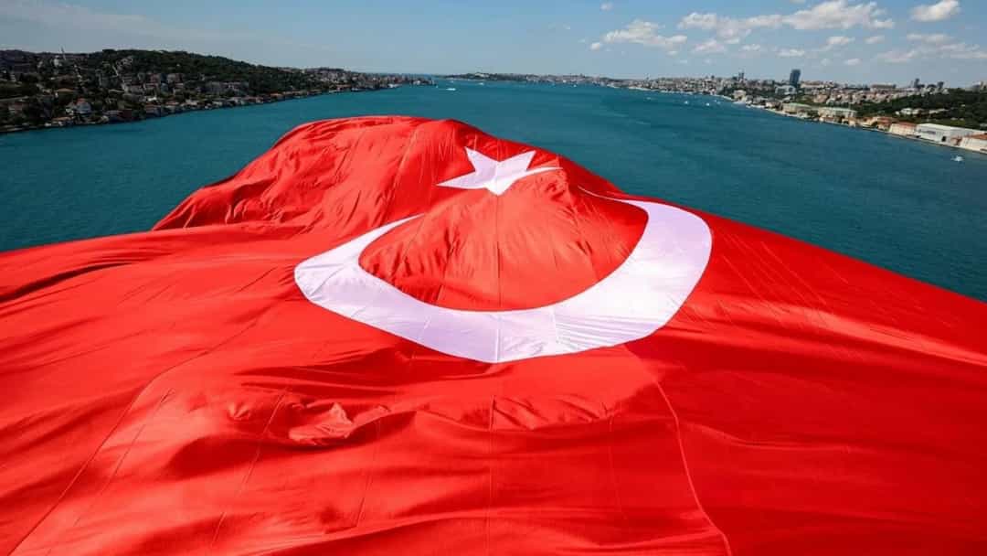Boğaz üzerinde serili büyük Türk bayrağı ve kıyıdaki yerleşim alanları