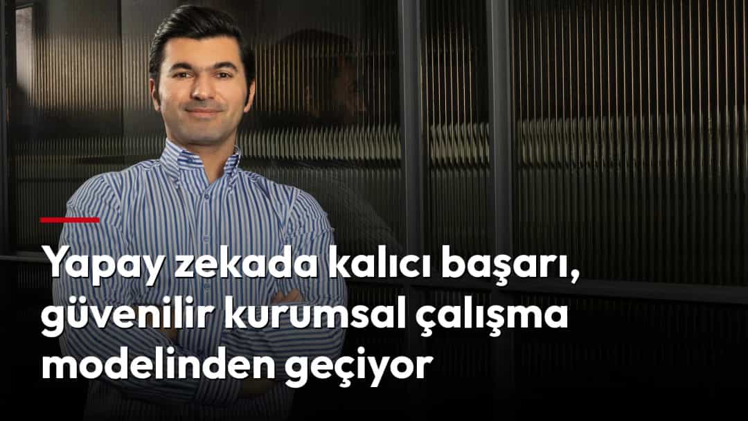 Zafer Şen, çizgili gömleğiyle modern bir ofiste kollarını kavuşturmuş halde duruyor.