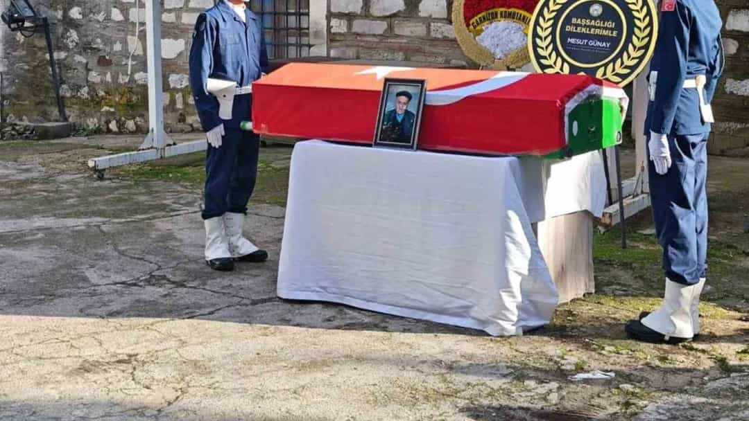 Türk bayrağına sarılı tabut, tören alanında askerlerin arasında duruyor.