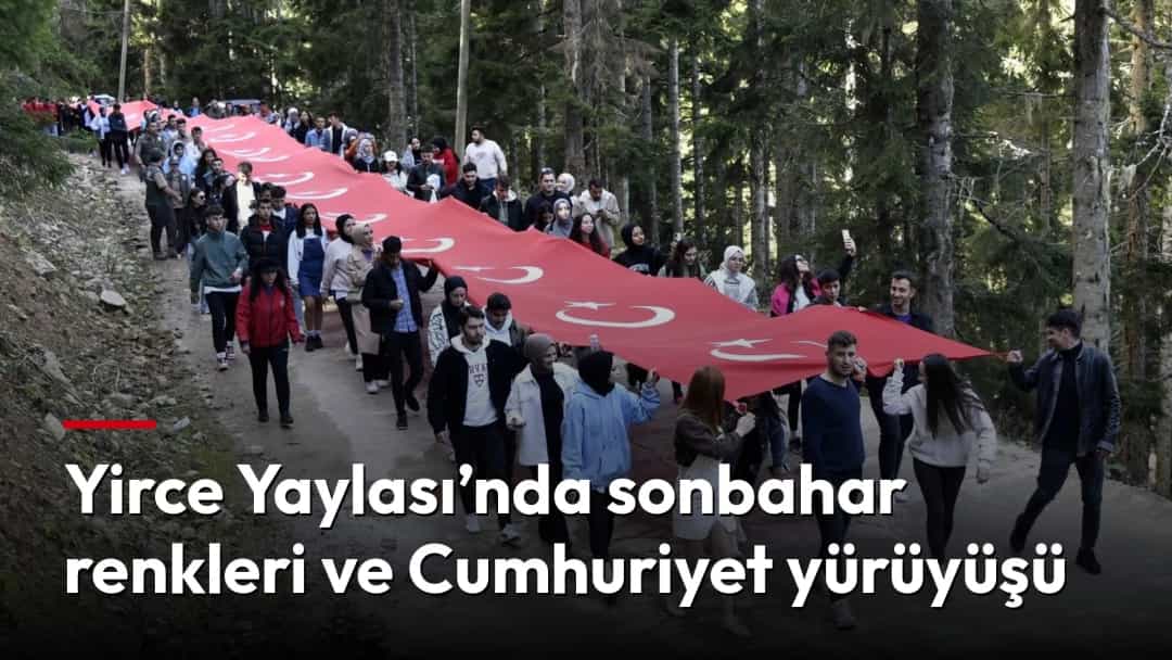 Sonbahar renklerine bürünen orman yolunda, büyük Türk bayrağı taşıyarak yürüyen kalabalık.