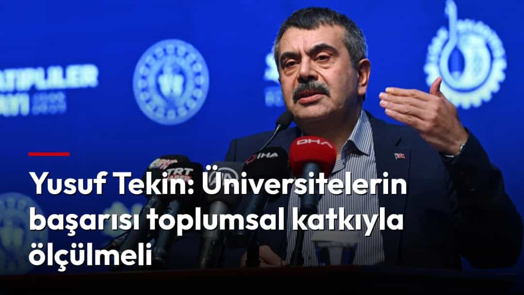 Yusuf Tekin, kürsüde konuşma yaparken mikrofonlarla çevrili.