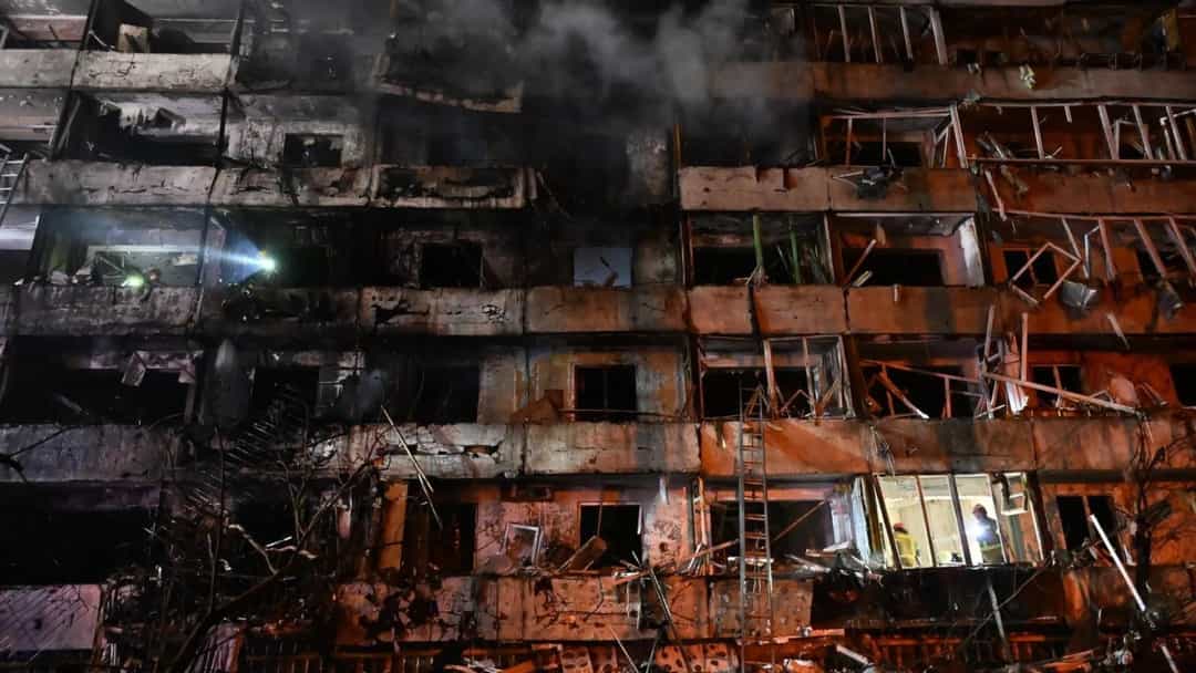 Dumanlar yükselen, ağır hasar görmüş bir apartman binası.